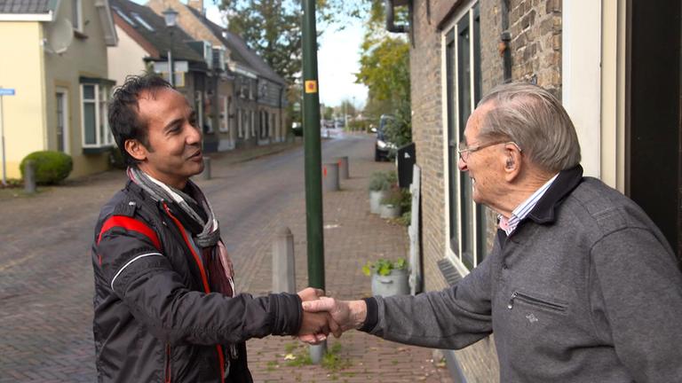 "plan b: Zuhause alt werden - Helfer statt Heim": Sandy Keppel begrüßt den 93-jährigen Jan Honkoop per Handschlag vor dessen Haus. Die beiden Männer lächeln sich an.