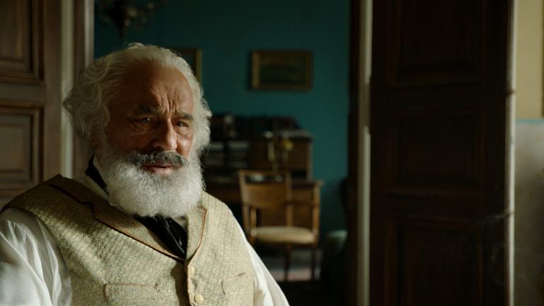"Karl Marx - der deutsche Prophet": Spielszene: Karl Marx (Mario Adorf) sitzt in seinem Wohnzimmer und schaut nachdenklich nach vorne.