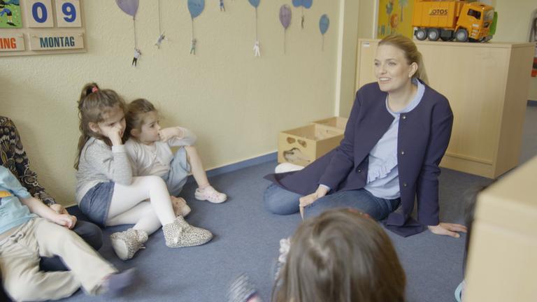 "Was Frauen wollen und Männer denken - Streitfall Emanzipation": Sarah Tacke sitzt mit Kindergartenkindern auf dem Boden.