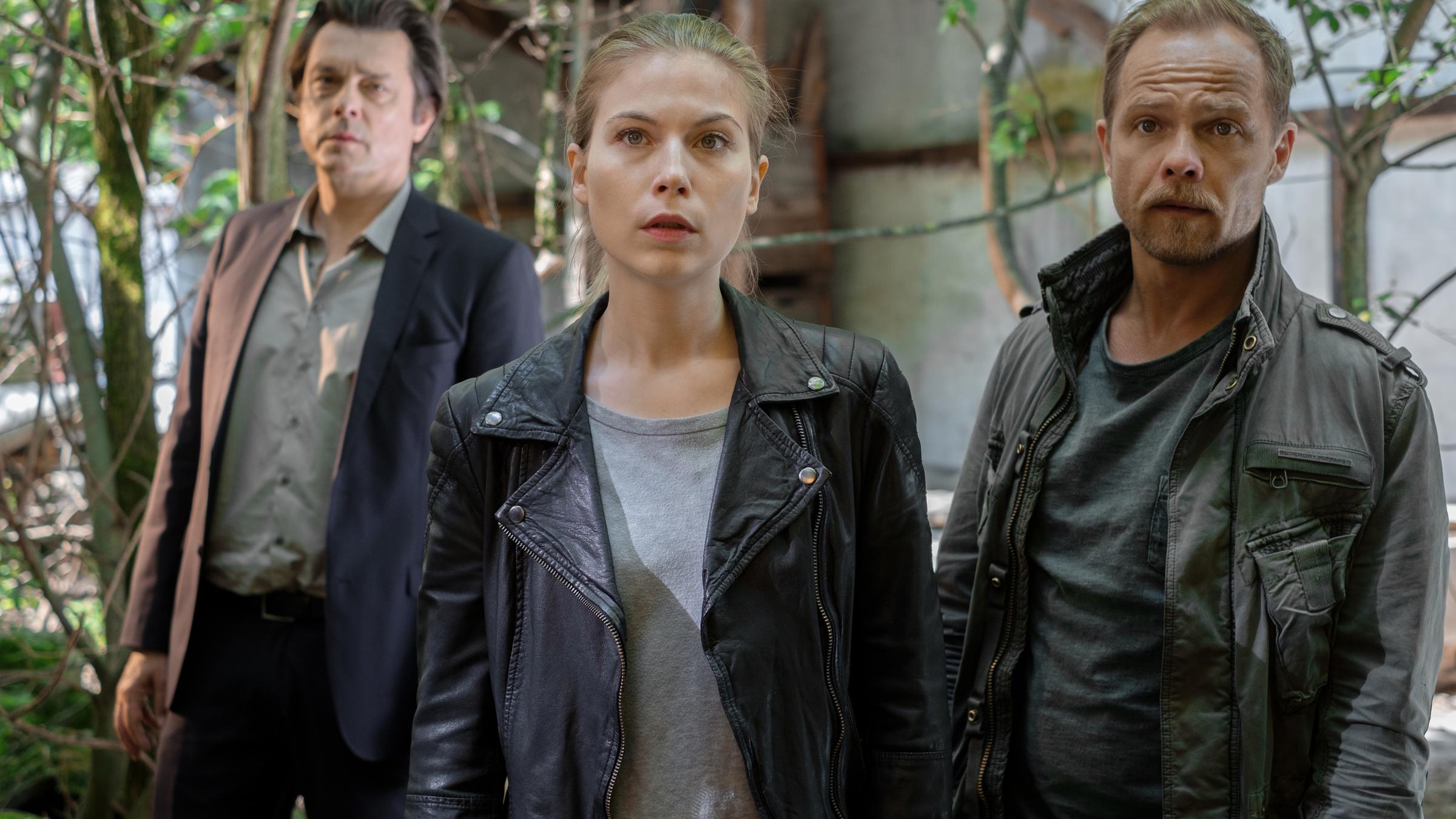 "Die Toten vom Bodensee - Die vierte Frau": Die drei Kollegen Komlatschek (Hary Prinz), Hannah Zeiler  (Nora Waldstätten) und Micha Oberländer (Matthias Koeberlin) stehen in einem Garten und schauen frontal in die Kamera.