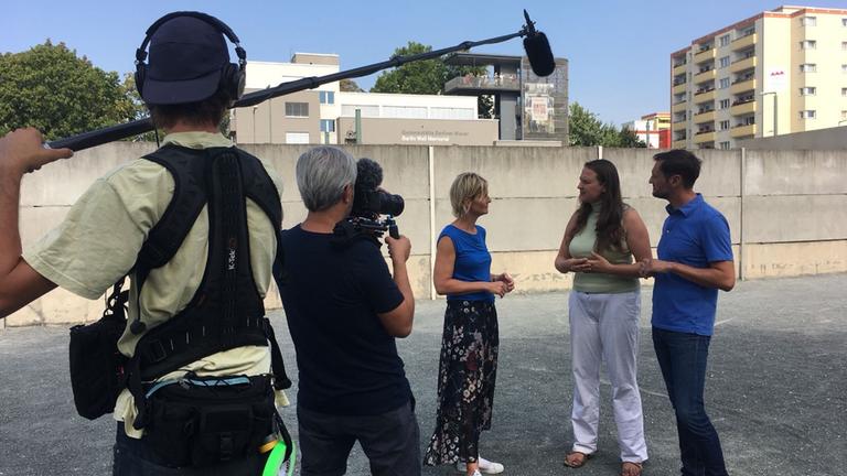 "Vereint und doch nicht eins - Barbara Hahlweg unterwegs im Osten Deutschlands": Die Autorin im Gespräch mit zwei Interviewpartnern und Kamerateam vor der Berliner Mauer .