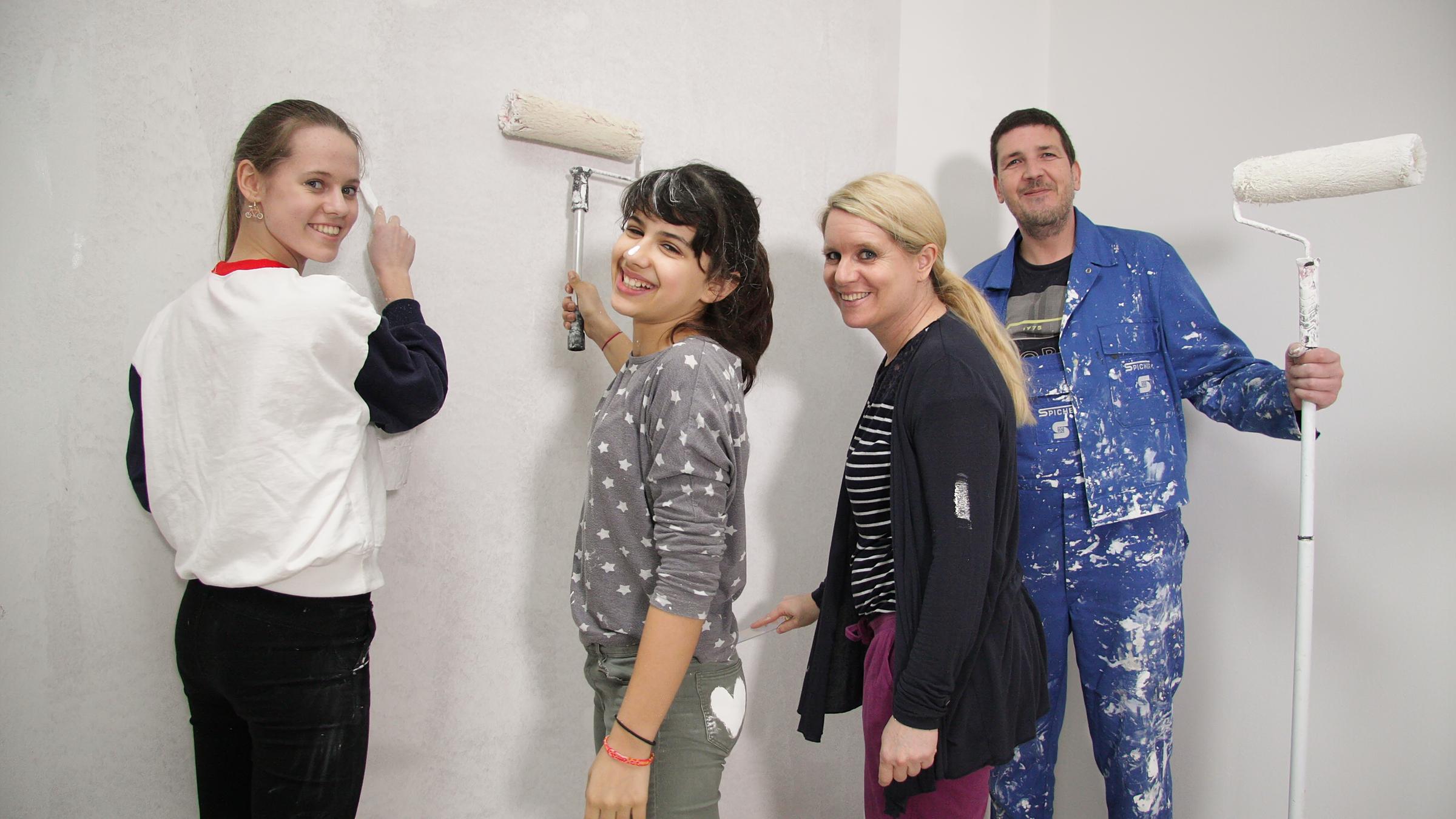 "37°: Eltern verzweifelt gesucht - Vom Kinderheim in die Pflegefamilie": Anne und Frank mit ihren Töchtern Lönja und Nermina. Alle zusammen streichen eine Wand an und lächeln in die Kamera.