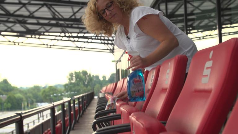 "37°: Arm trotz Arbeit - Wenn ein Job nicht reicht": Sabine beugt sich zum Reinigen im Fußballstadion über die Stuhlreihen im Zuschauerbereich.