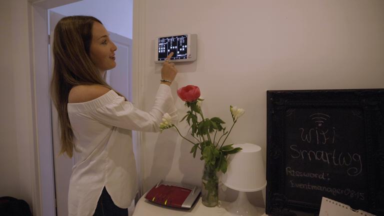 "planet e.: Stromfresser Internet - Die Schattenseiten der Digitalisierung":  Eine Frau steht vor dem Steuerungsgerät an der Wand und tippt etwas ein.