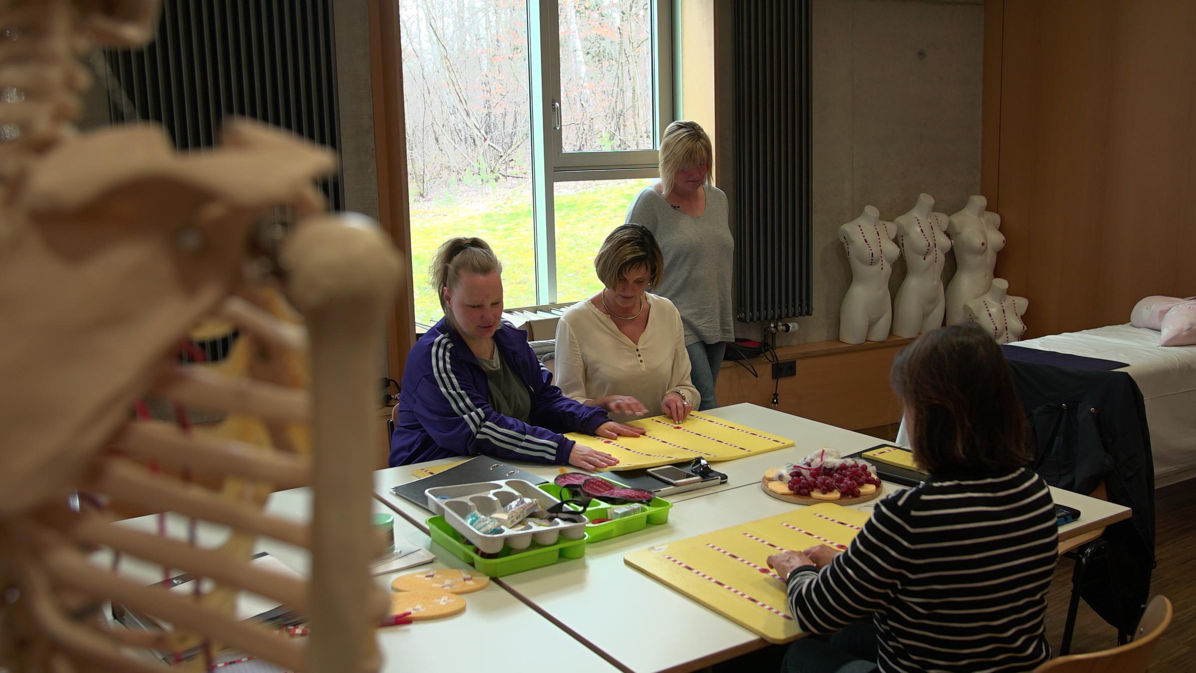 "plan b: Scharfblick und Fingerspitzengefühl - Mit Behinderung zum Traumjob": Mehrere Frauen sitzen an einem Tisch vor Tastplatten und üben ihre Fähigkeiten.