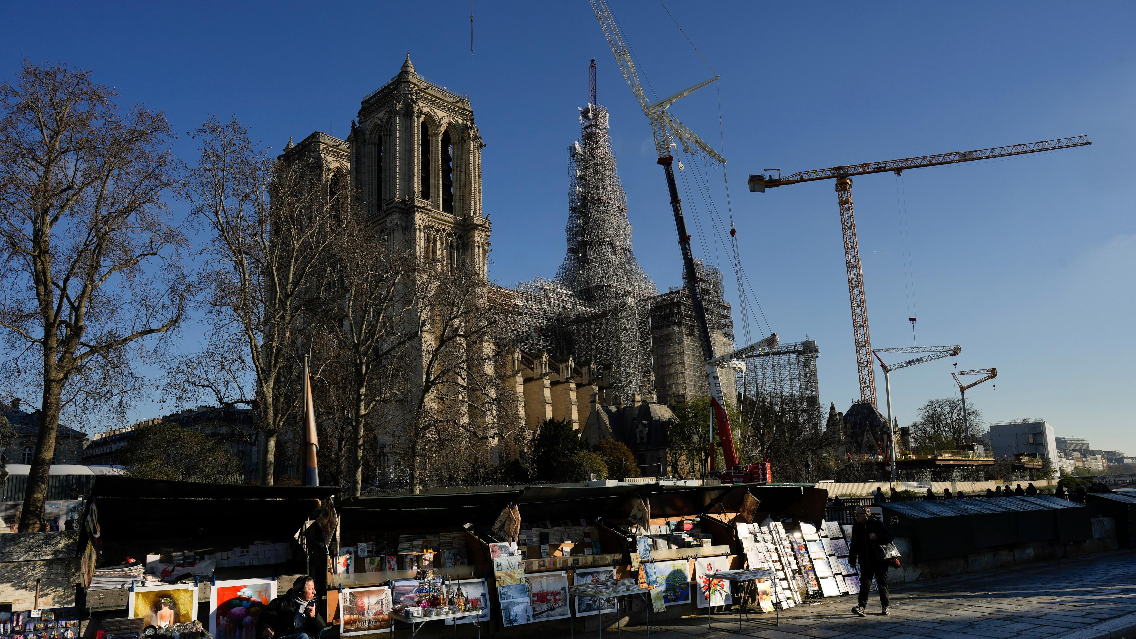 Eine riesige Kathedrale, die Notre-Dame in Paris, ist von Gerüsten und Kränen umgeben.