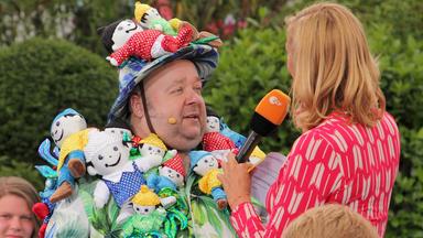 "ZDF-Fernsehgarten": Dirk Bach 2011 im Gespräch mit Andrea Kiewel. Er trägt ein Kostüm und einen Hut aus lauter Stoff-Mainzelmännchen.