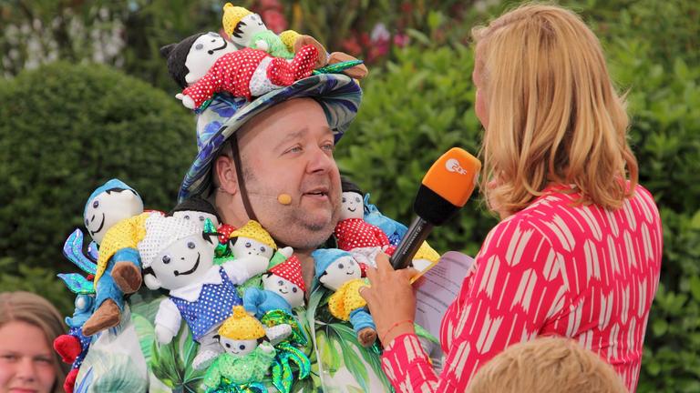 "ZDF-Fernsehgarten": Dirk Bach 2011 im Gespräch mit Andrea Kiewel. Er trägt ein Kostüm und einen Hut aus lauter Stoff-Mainzelmännchen.