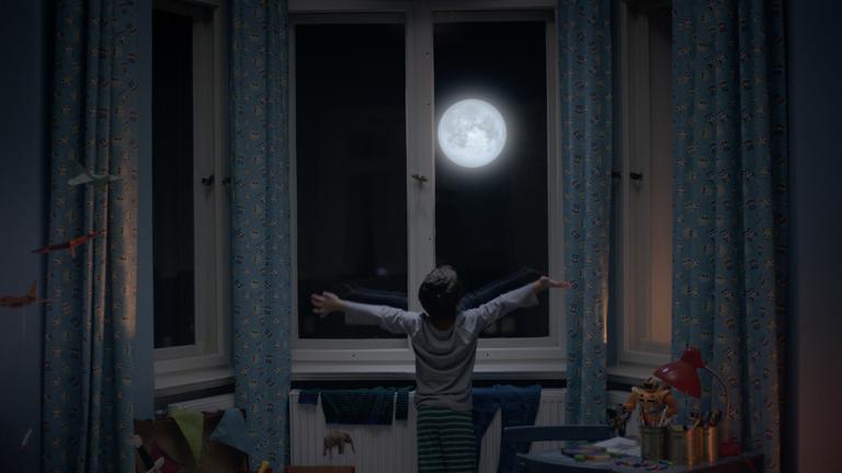 Siebenstein: „Der Mond und ich“: Ein kleiner Junge steht nachts vor dem Fenster und breitet die Arme aus, wie um den großen, hereinscheinenden Mond zu begrüßen.
