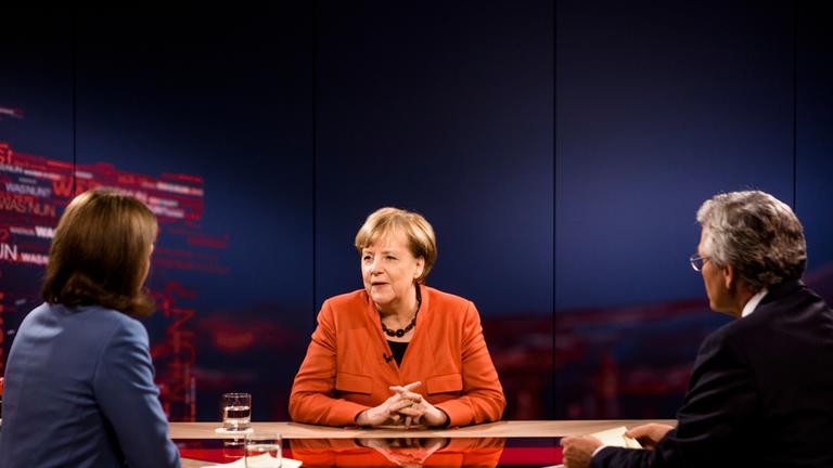 Archiv: "Was nun, Frau Merkel?": Bettina Schausten, Angela Merkel und Peter Frey sitzen zum Gespräch an einem Tisch.