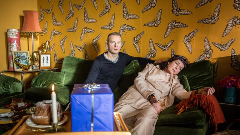 "Der mit dem Schlag": Felix Grünler (Hinnerk Schönemann) sitzt auf der Couch und schaut entsetzt nach vorne. Neben ihm ist seine tote Mutter (Elisabeth Trissenaar) zu sehen.
