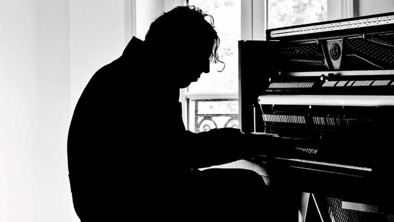 "Shut up and play the piano – Chilly Gonzales" (ARTE): Der kanadische Musiker Chilly Gonzalez sitzt am Piano und spielt (Schwarzweiß-Gegenlicht Aufnahme)