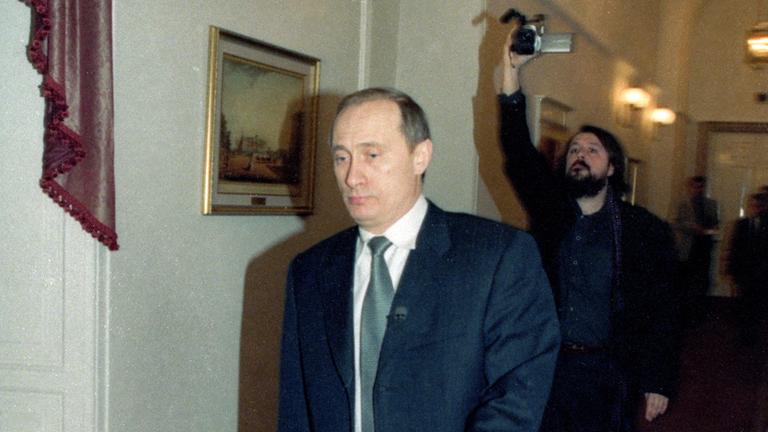 "Putins Zeugen" (ARTE):  Der junge Wladimir Putin läuft durch einen Flur. Hinter ihm läuft Filmemacher Vitaly Mansky und filmt Putin mit einem Camcorder.