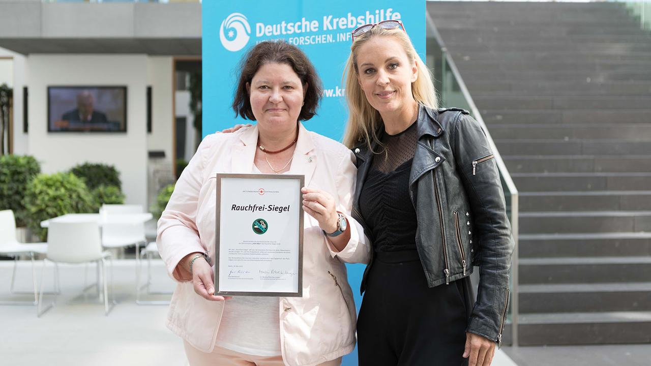Verleihung "Rauchfrei-Siegel" 2018 in Berlin: Silvia Lambri mit der Auszeichnungsurkunde (l.) und Lilian Klebow (r.)
