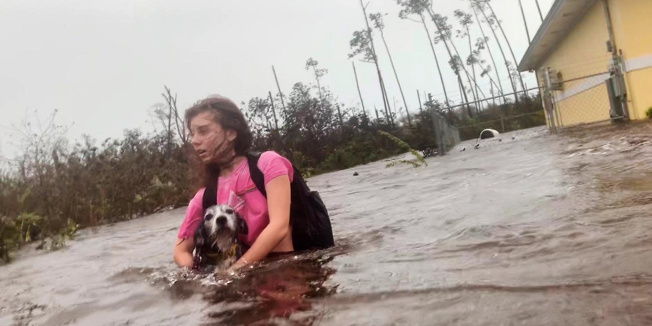 Julia Aylen watet mit ihrem Hund durch hüfthohes Wasser auf einer überfluteten Strasse, aufgenommen am 03.09.2019 in Freeport (Bahamas)
