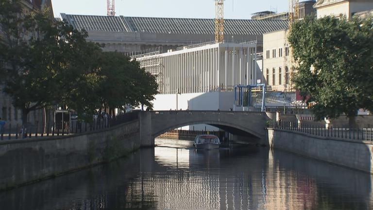 "Ein Eingang für die Ewigkeit": Das neue Eingangsgebäude der Museumsinsel – die James Simon Galerie. Davor ist eine Brücke. Unter der Brücke fährt ein Boot.