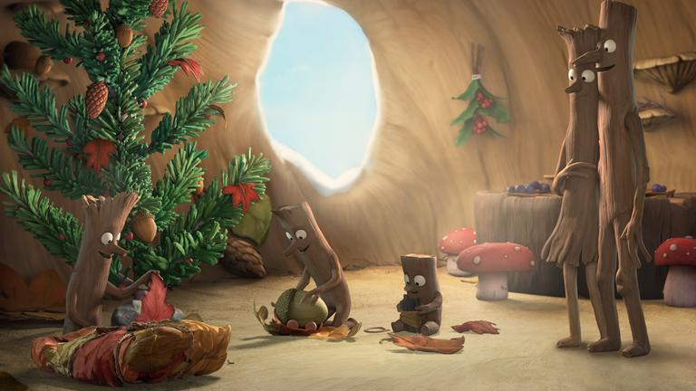 "Stockmann": Stockmann steht neben seiner Frau, die er im Arm hält. Sie schauen auf ihre Stockkinder, die vor dem Weihnachtsbaum die Weihnachtsgeschenke auspacken. Alle lächeln sehr glücklich.