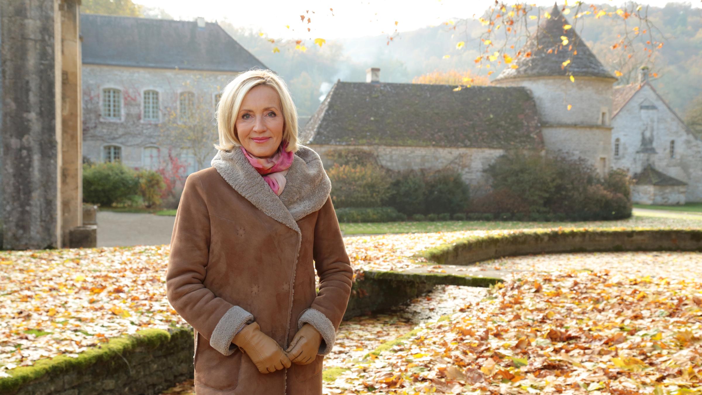 "Das Imperium der weißen Mönche - Petra Gerster auf den Spuren der Zisterzienser": Petra Gerster steht im Herbstlaub vor der im 12. Jahrhundert errichteten Zisterzienserabtei von Fontenay.