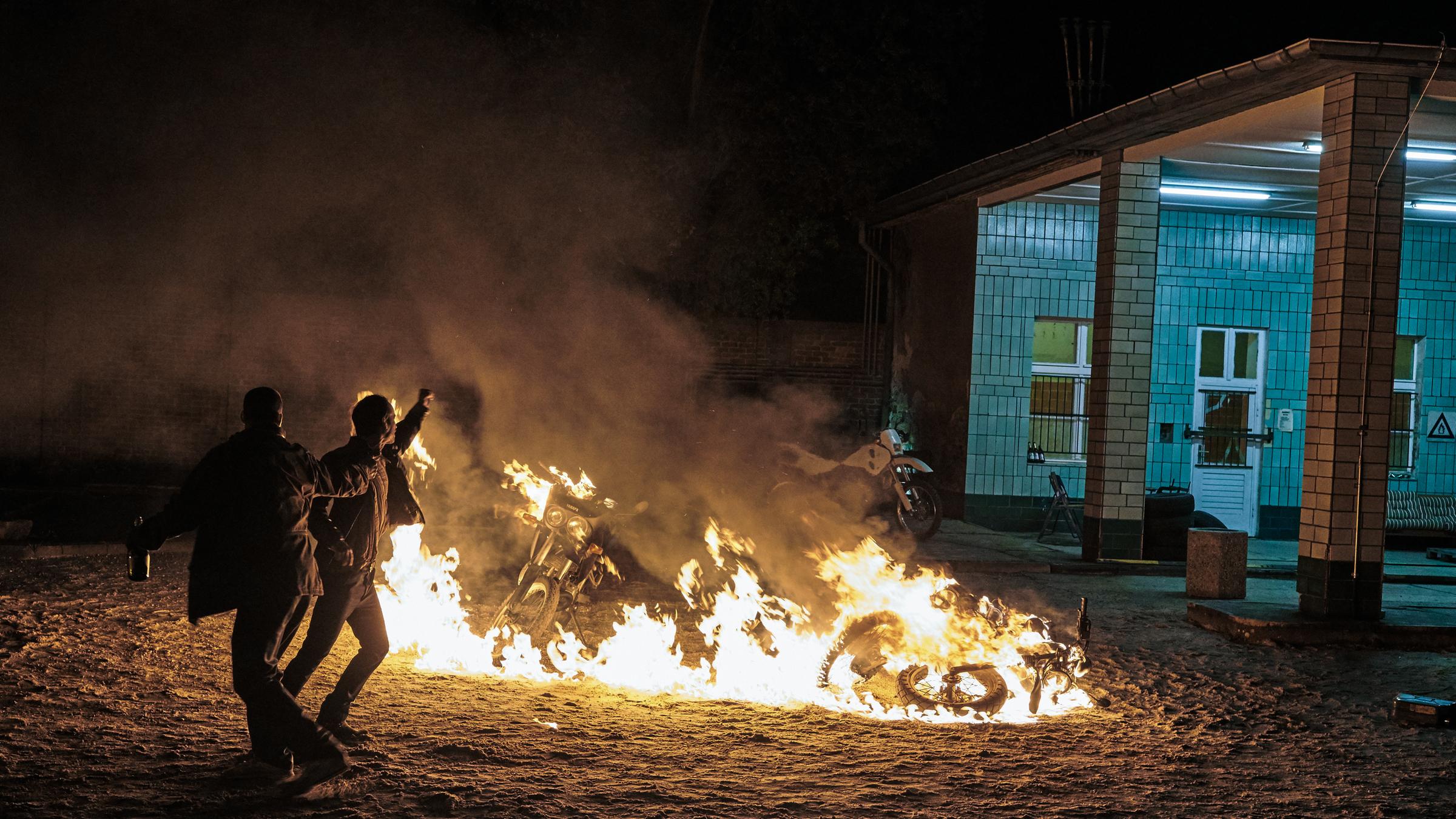   "Tempel - Nur ein Kampf": Mark (Ken Duken) und Adrian (Maximilian Brauer) stehen vor einem Berg brennender Motorräder.