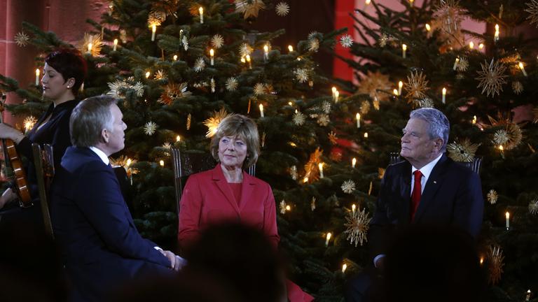 "Weihnachten mit dem Bundespräsidenten": Johannes B. Kerner im Gespräch mit Bundespräsident Gauck und Frau Schadt. Sie sitzen vor geschmückten Weihnachtsbäumen.