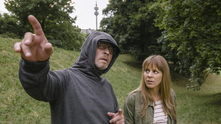 „München Mord - Wo bist du, Feigling": Kommissar Schaller (Alexander Held) will den Tathergang rekonstruieren, er spielt den vermummten Jogger. Angelika Flierl (Bernadette Heerwagen) steht neben ihm und lässt sich etwas erklären.