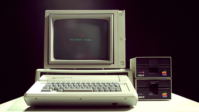 "Geheimnisse der digitalen Revolution - PC's erobern die Welt": Ein Computer mit Tastatur, Bildschirm und Laufwerken auf einem Schreibtisch vor schwarzem Hintergrund.