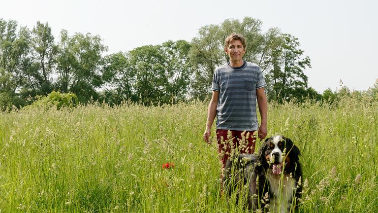 "Löwenzahn: Wiese - Grüne Wildnis in Gefahr": Fritz (Guido Hammesfahr) läuft mit seinem Hund Keks über eine Wildwiese.