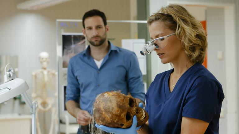 "Die Spezialisten - Im Namen der Opfer: Traumhafte Zeiten": Im Labor untersucht Dr. Katrin Stoll (Valerie Niehaus) einen Schädel den sie in der Hand hält. Henrik Mertens (Matthias Weidenhöfer) schaut ihr zu.