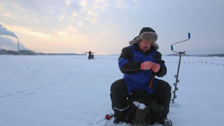 Let it snow": Ein Mann angelt an einem Eisloch.