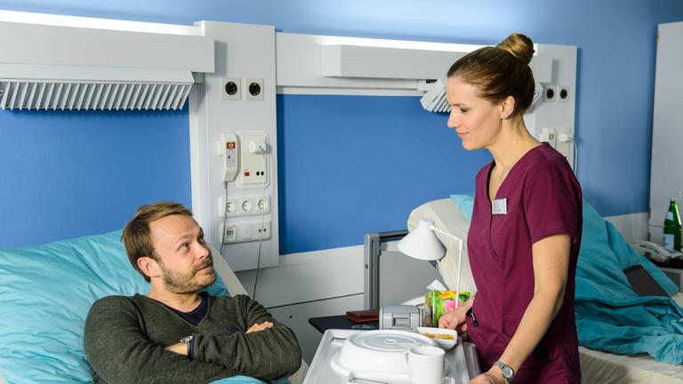 "Bettys Diagnose - Undercover Boss": Patient Schneider (Matthias Ziesing) bekommt von Betty (Bettina Lamprecht) das Essen ans Krankenbett gebracht.