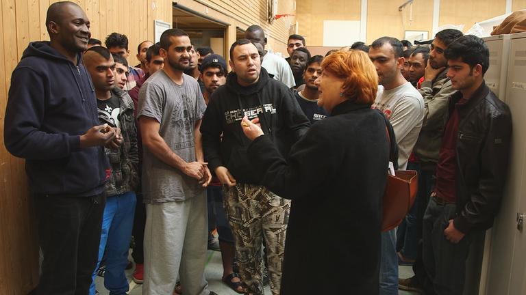 "ZDFzoom: Nachgezoomt 2017 - Was aus unseren Geschichten wurde": Autorin Rita Knobel-Ulrich im Gespräch mit Flüchtlingen in einer Turnhalle.