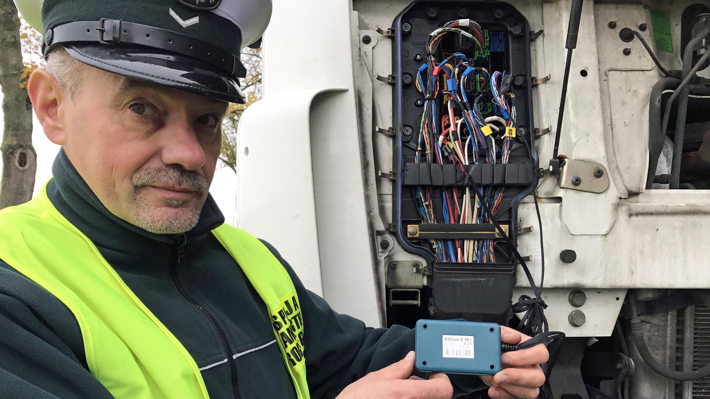 "ZDFzoom: Die Lüge vom sauberen LKW - Abgas-Betrüger und ihre Dreckschleudern": Polnischer Polizist hält einen AdBlue-Emulator in die Kamera.