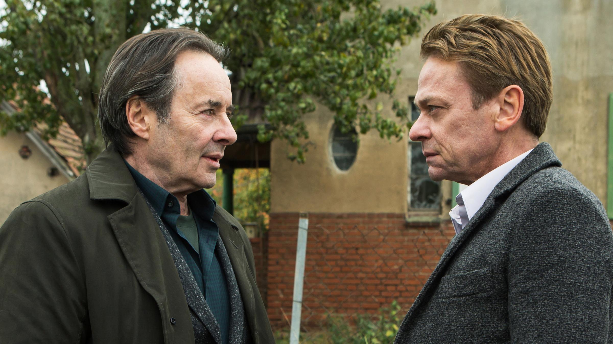 "Ein Kommissar kehrt zurück": Günther Kovak (Uwe Kockisch) und Prof. Michael Adam (Sylvester Groth) stehen sich gegenüber und schauen sich mit ernstem Blick an.