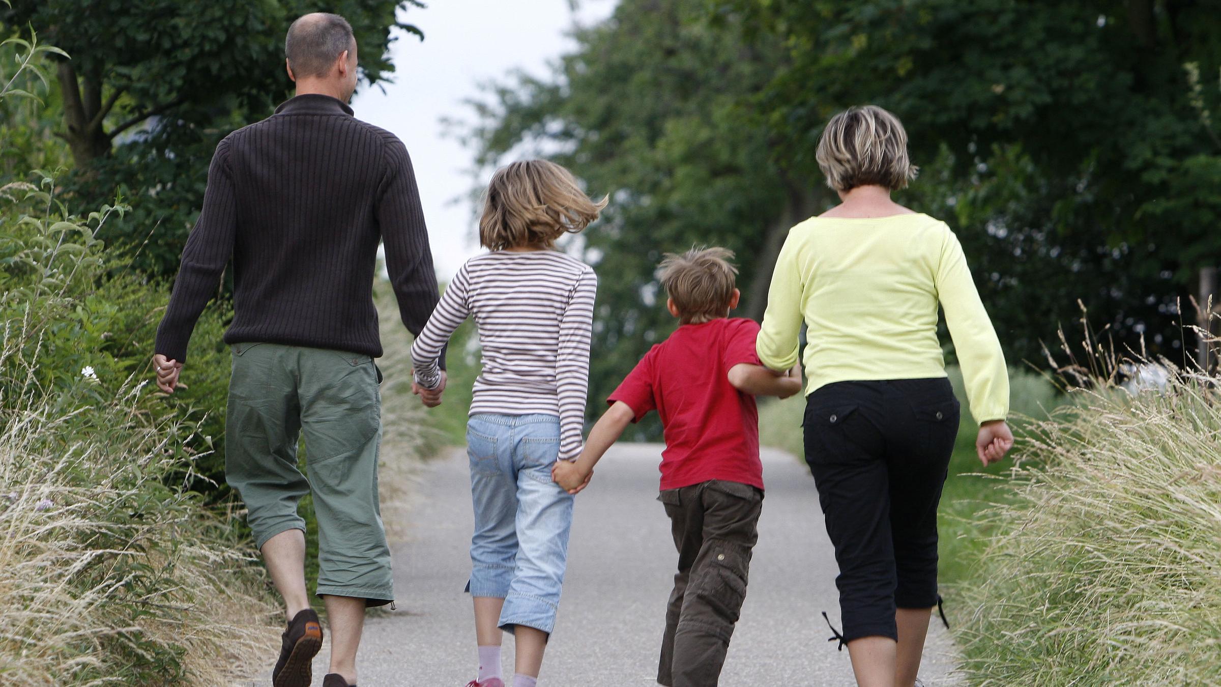 Kinder hüpfen mit ihren Eltern auf einem Weg.