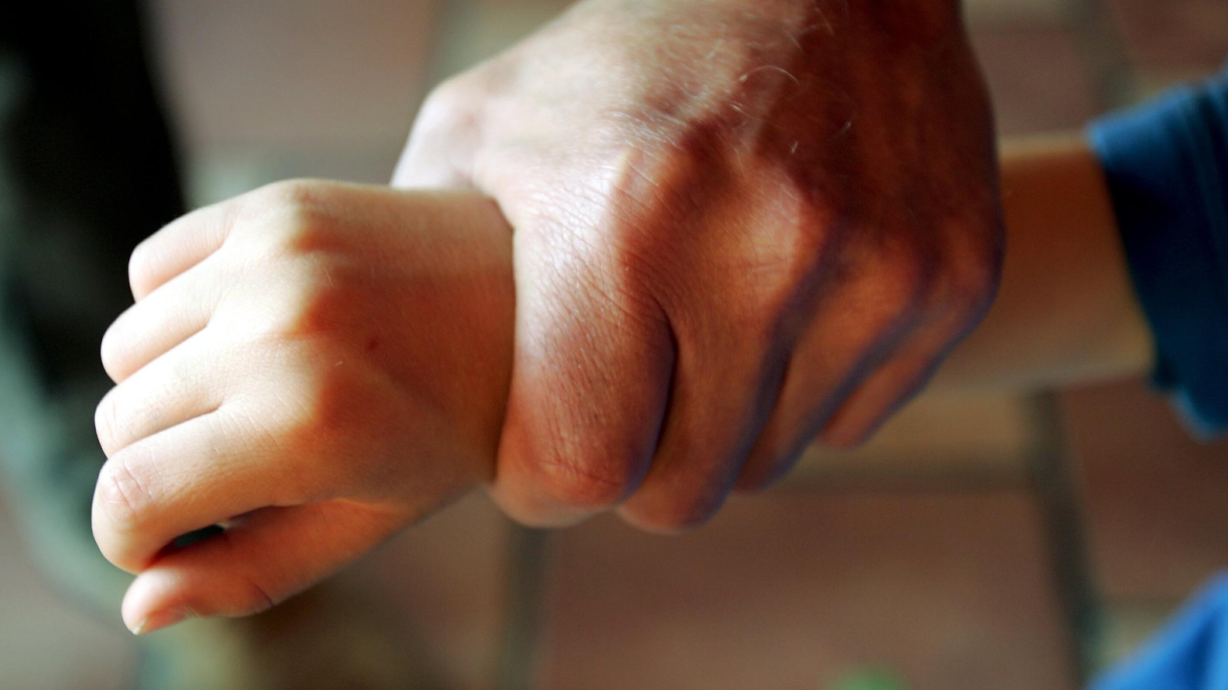 Ein Kind wird am Arm gepackt.