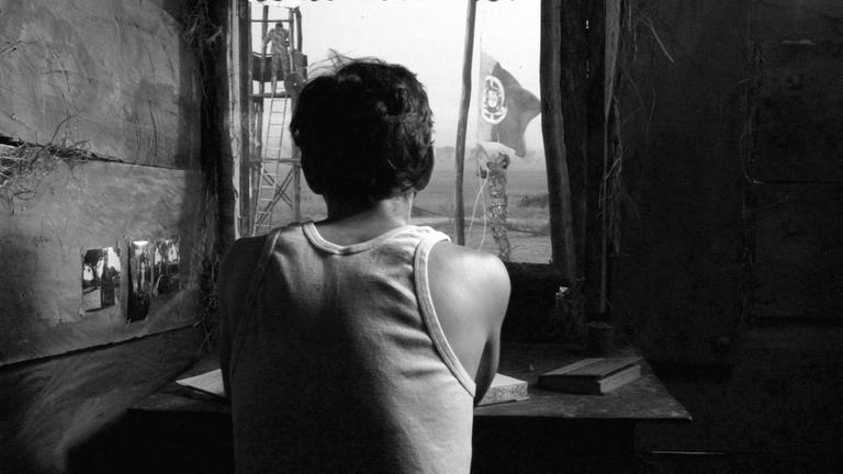 "Briefe aus dem Krieg": António (Miguel Nunes) sitzt mit dem Rücken zur Kamera am Fenster und schreibt einen Brief.