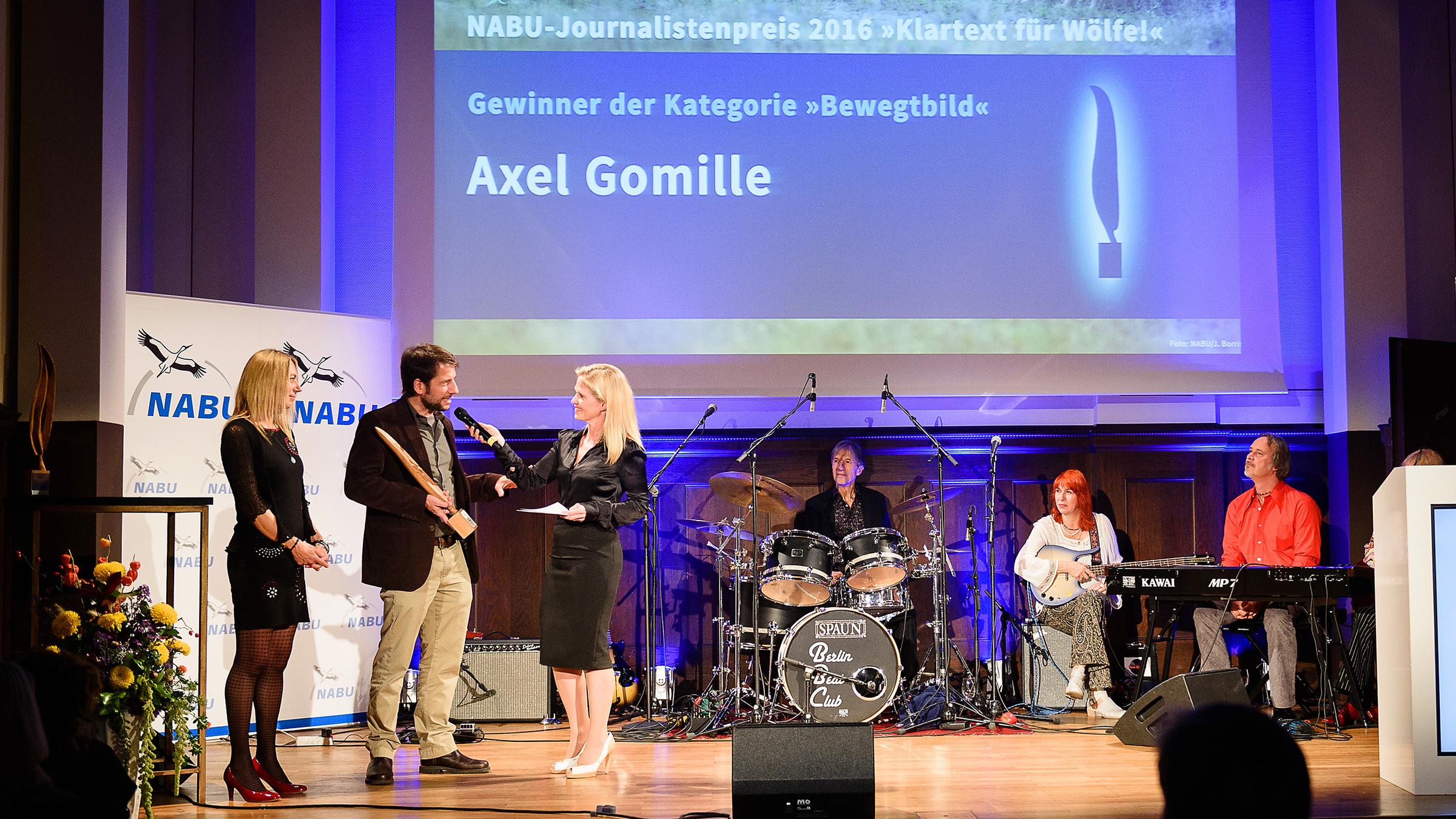 Axel Gomille, Autor und Regisseur der Dokumentation “Wölfe im Visier“, nimmt den Journalistenpreis des Naturschutzbund Deutschland in Berlin entgegen. (v.l.n.r.): Angelika Richter (NABU), Axel Gomille (ZDF) und Moderatorin Kerstin von der Linden