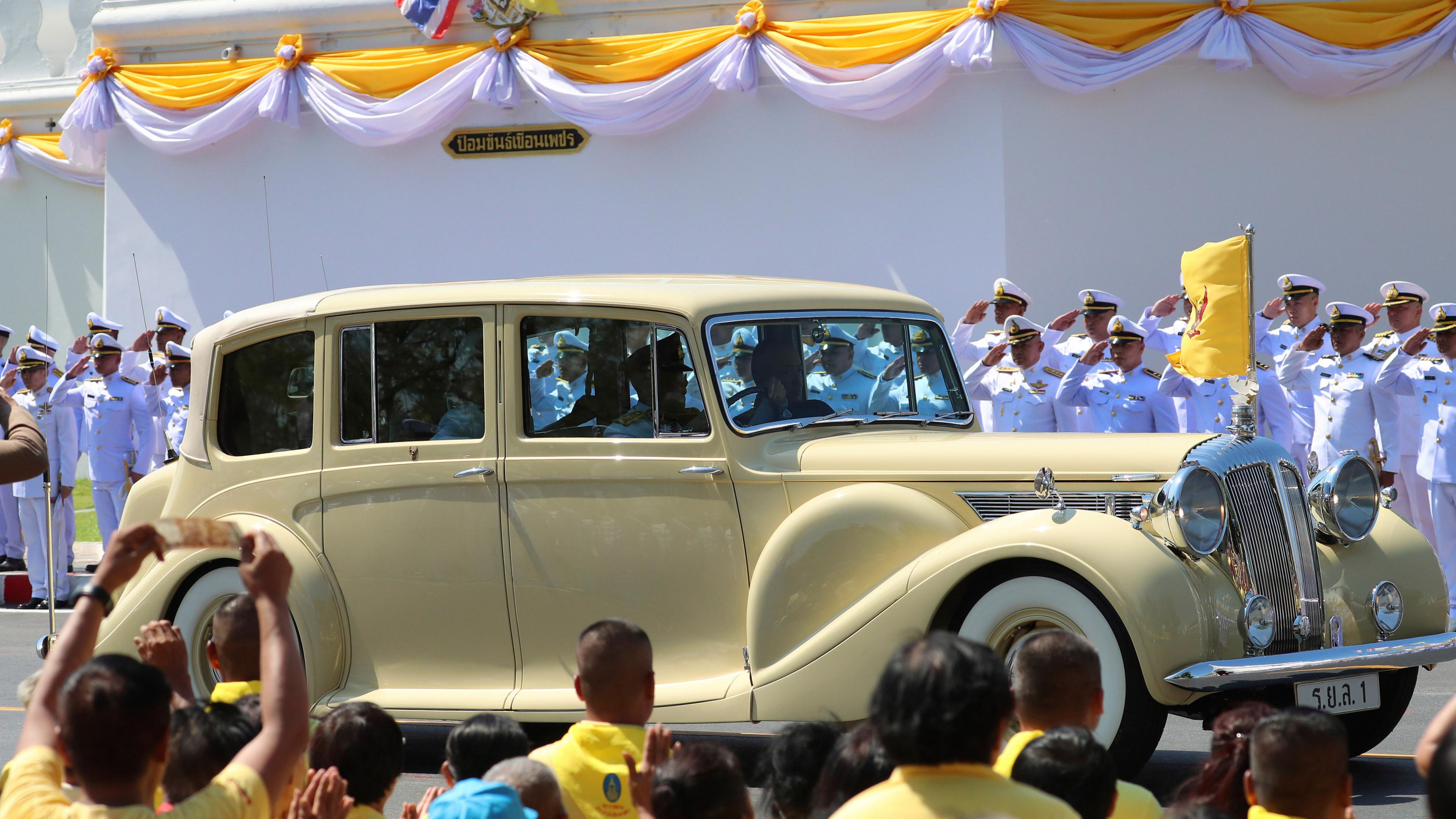 König Maha Vajiralongkorn und Königin Suthida fahren in einer Limousine während der Krönungsfeierlichkeiten am 4. Mai 2019 in Bangkok an wartenden Menschen vorbei.