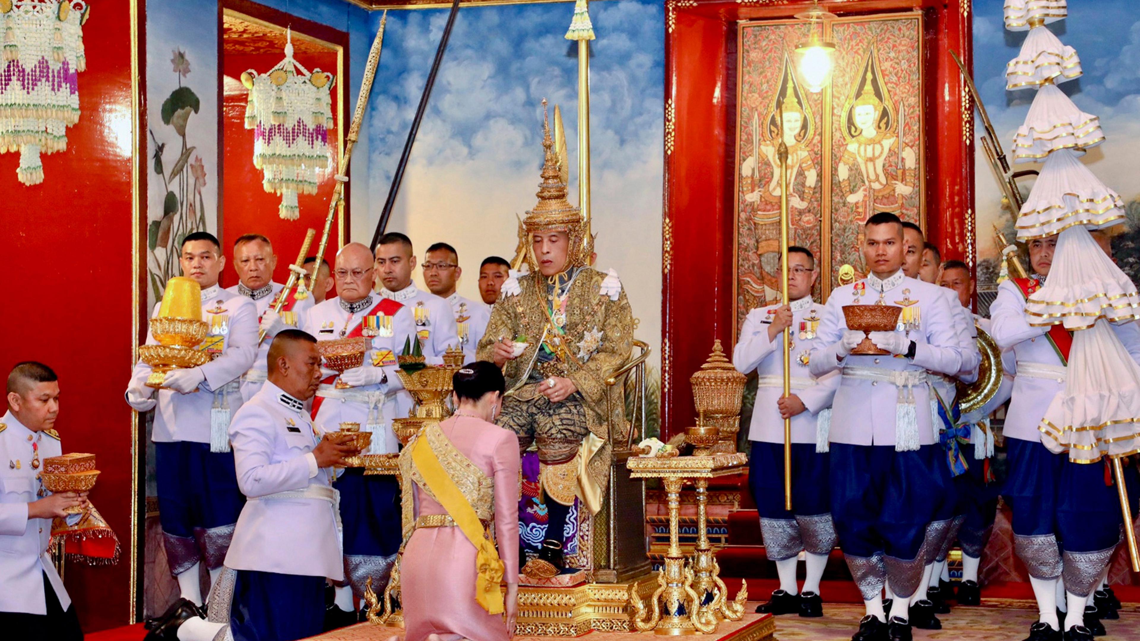 Maha Vajiralongkorn (m.) sitzt anlässlich seiner Krönung am 04. Mai 2019 auf dem Thron, während Königin Suthida vor ihm kniet.