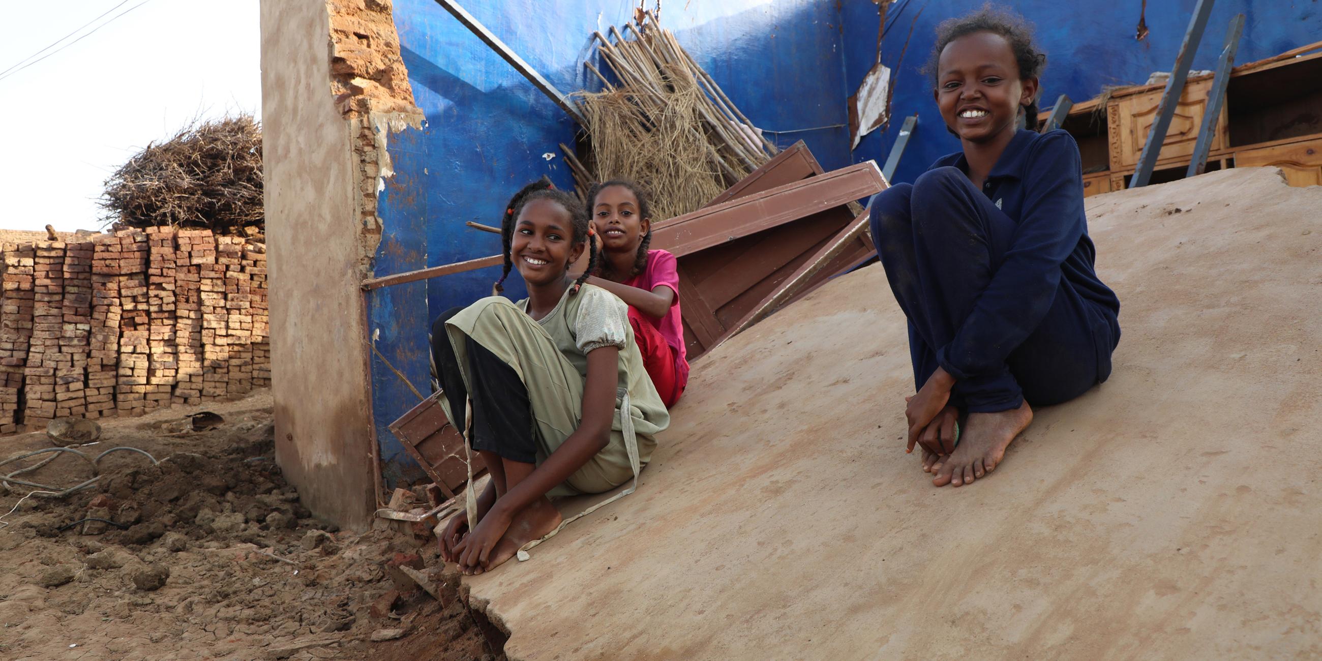 Sudanesische Kinder posieren für Fotos auf ihrem von Überschwemmungen zerstörten Haus