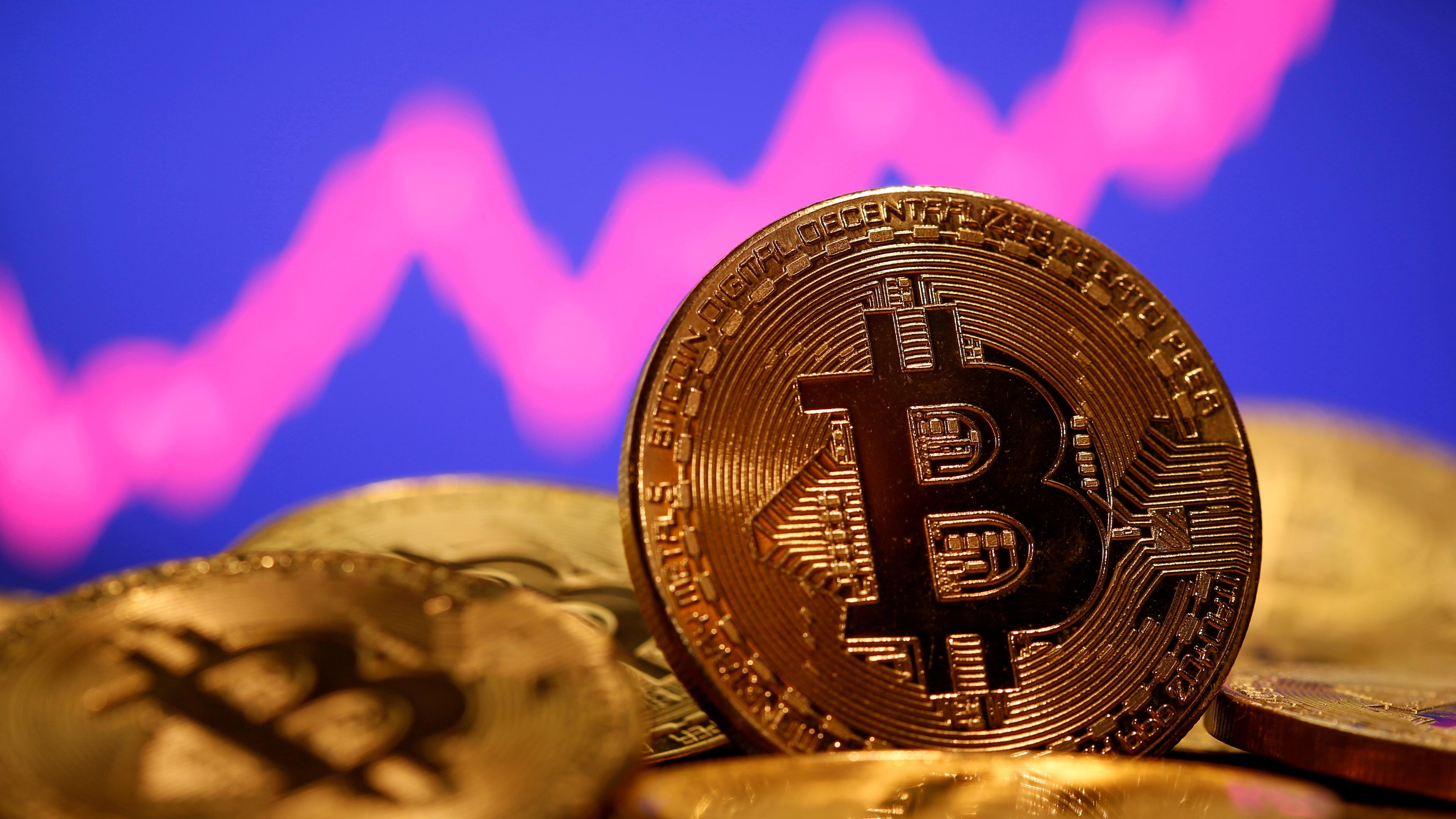 Eine Bitcoin-Münze steht vor einer virtuell steigenden Kurve