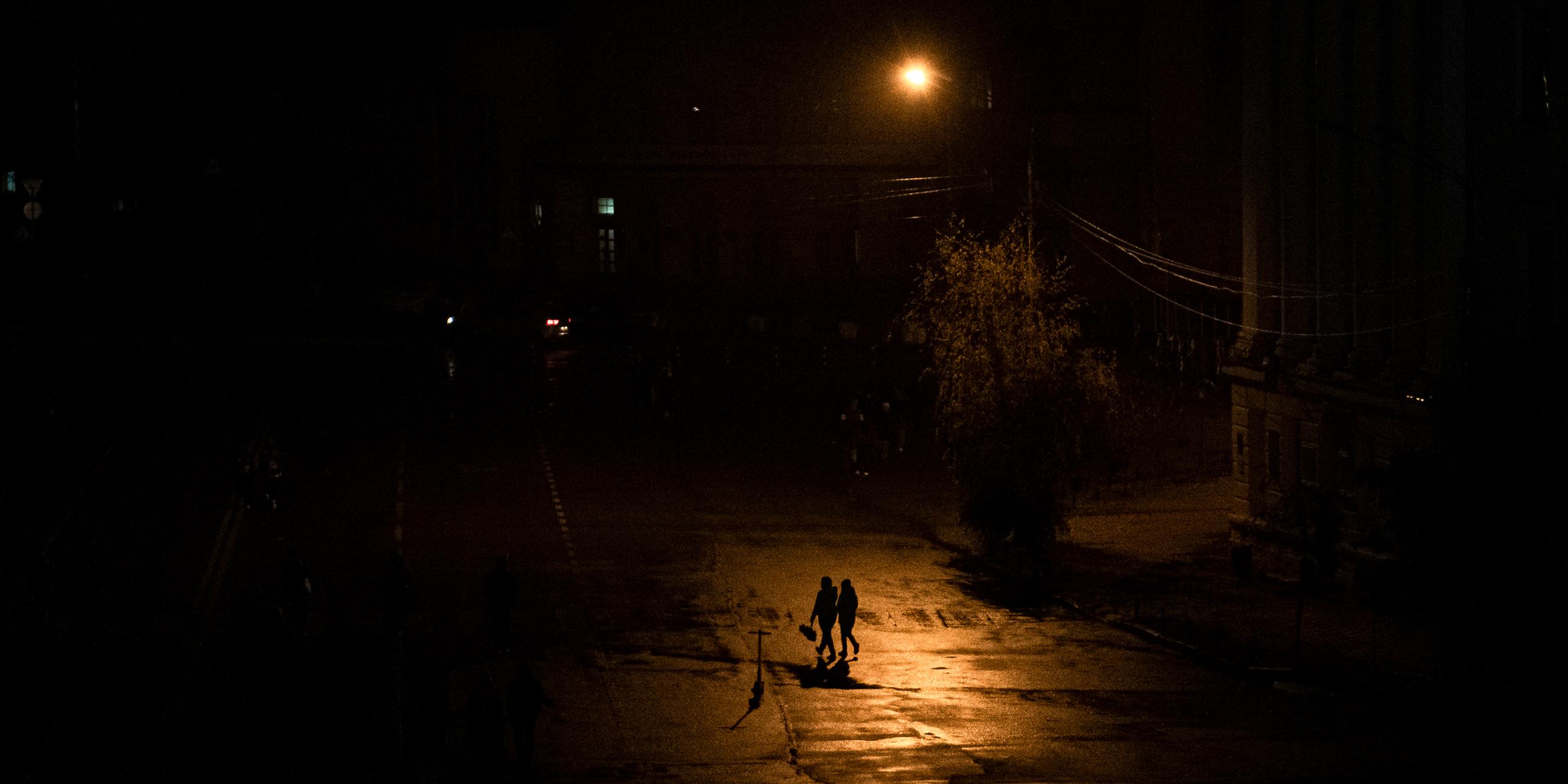 Menschen gehen während eines Stromausfalls in Kiew über eine Straße.