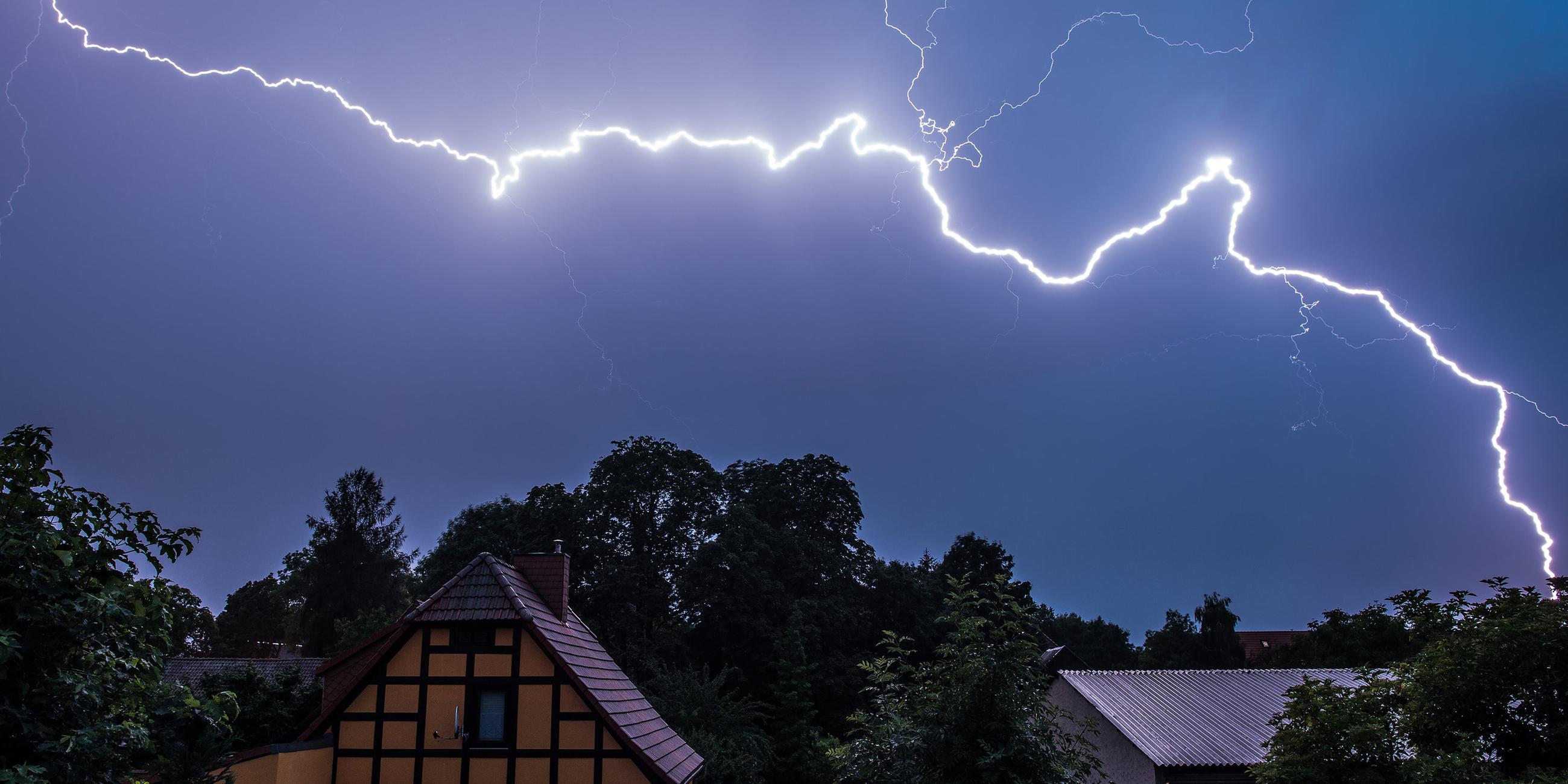 Ein starker Blitz leuchtet am Nachthimmel am 07.07.2015 über Häusern in Sieversdorf im Landkreis Oder-Spree (Brandenburg) auf
