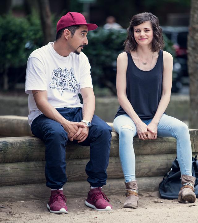 Sol und Jessica sitzen auf dem Rand eines hölzernen Blumenbeetes im Hof.