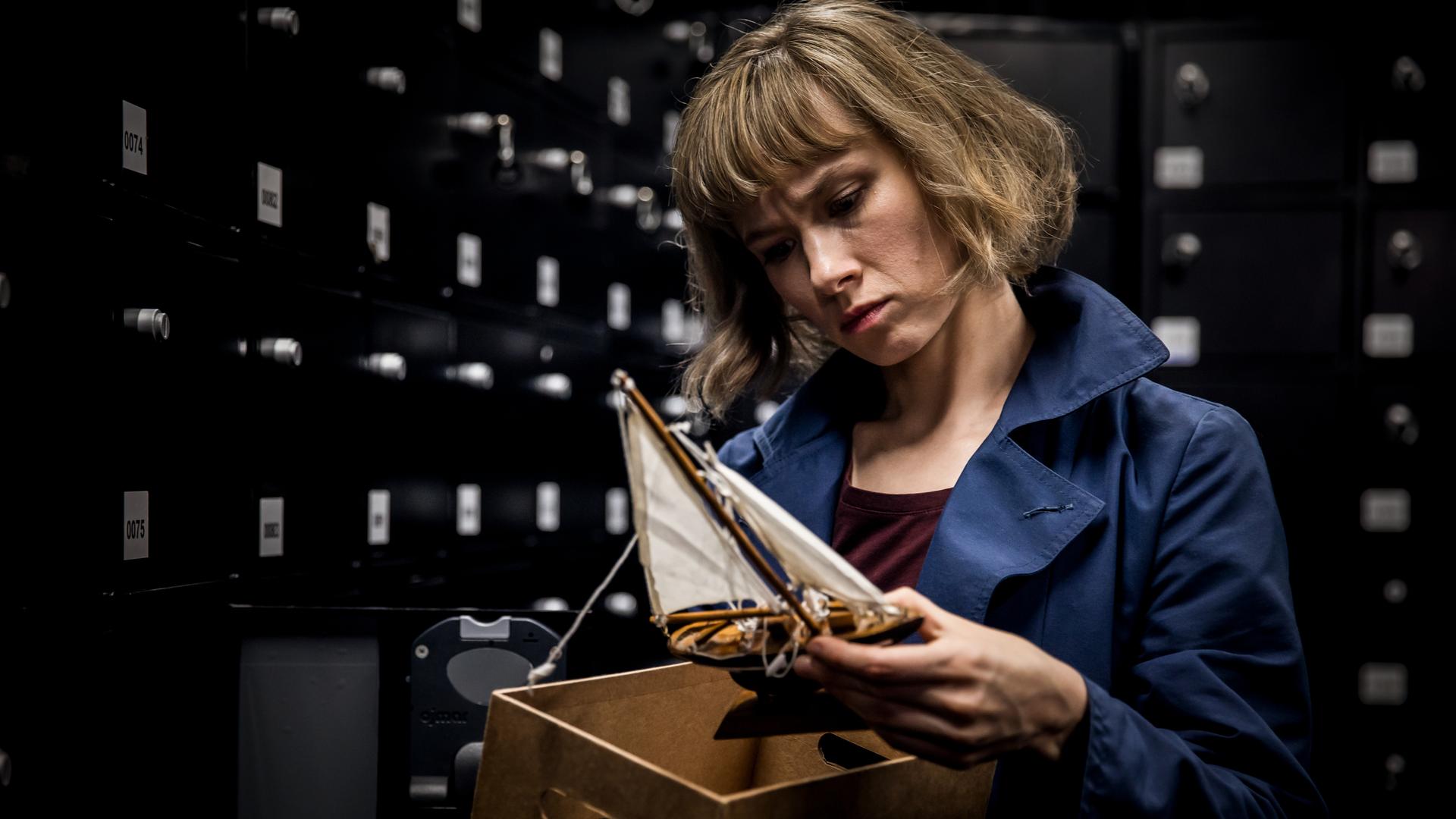 Eine Nahaufnahme von Doro Decker (Alina Levshin), die ein Spielzeugschiff in den Händen hält und inspiziert.