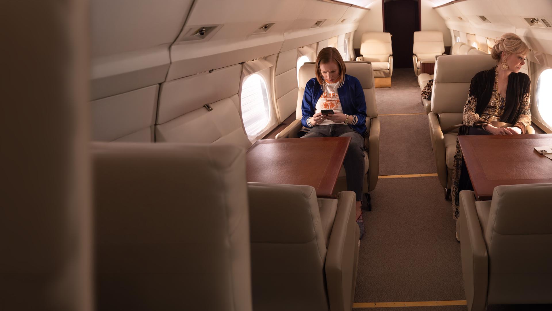 "Hacks - Blut wird fließen": Ava (Hannah Einbinder) und Deborah (Jean Smart) sitzen in einer luxuriösen Flugzeugkabine. Während Ava vertieft auf ihr Handy schaut, richtet Deborah ihren Blick nachdenklich aus dem Fenster des Flugzeugs.