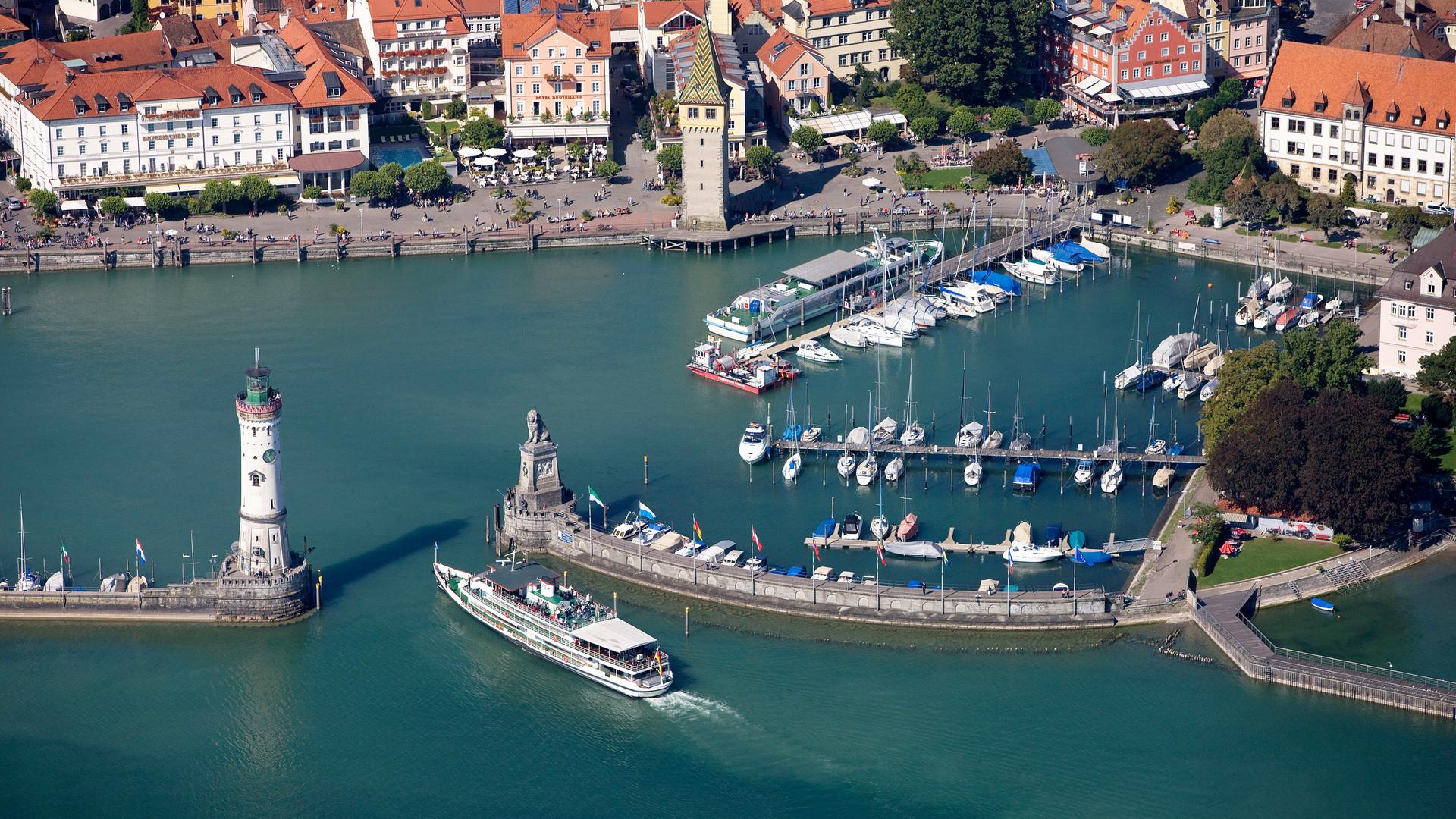 "ZDF.reportage: Bodensee - Urlauberlust und Anwohnerfrust": Luftaufnahme: Blick auf die Hafeneinfahrt von Lindau am Bodensee. Ein Ausflugsdampfer fährt gerade dort ein.