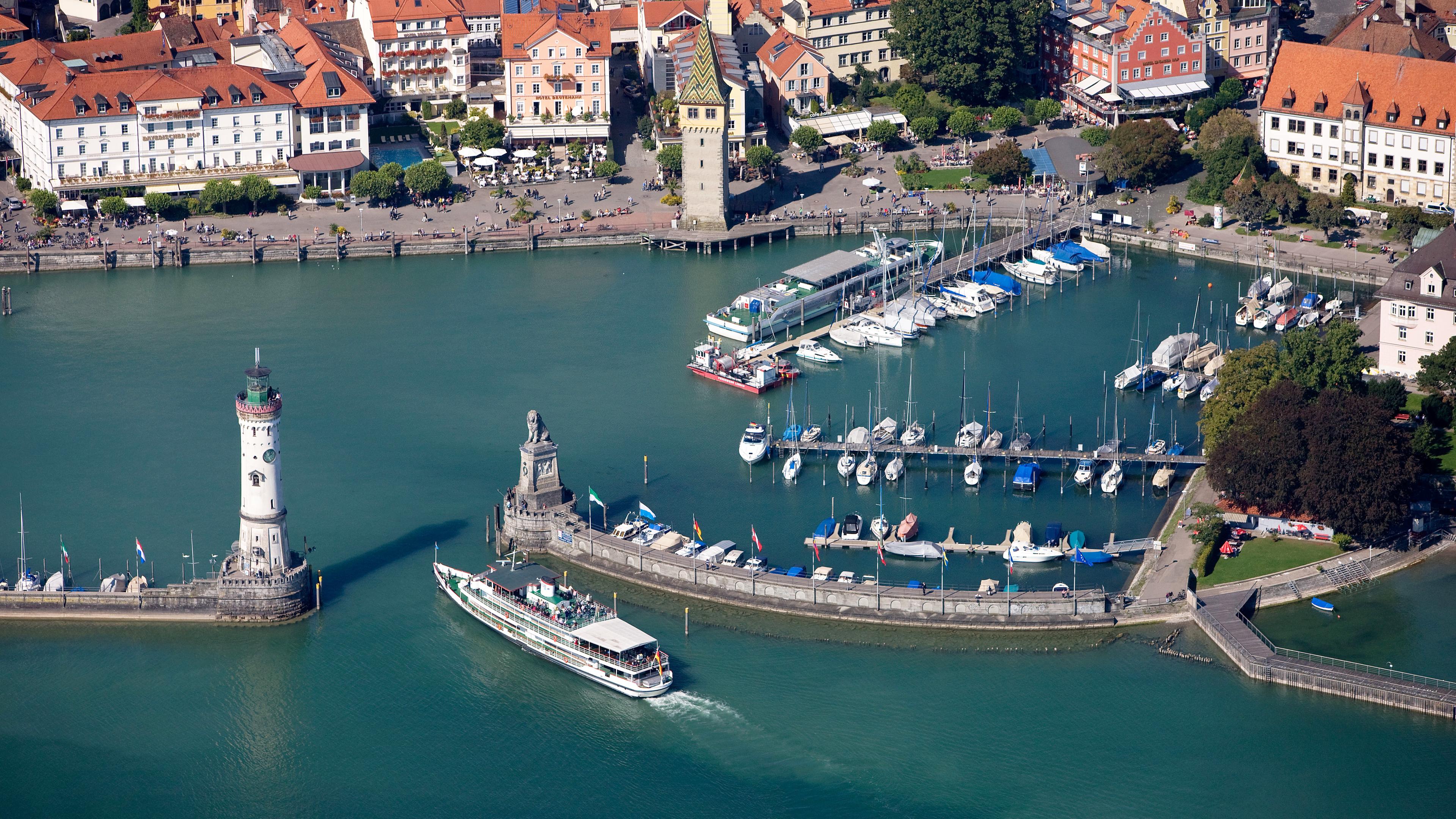 "ZDF.reportage: Bodensee - Urlauberlust und Anwohnerfrust": Luftaufnahme: Blick auf die Hafeneinfahrt von Lindau am Bodensee. Ein Ausflugsdampfer fährt gerade dort ein.