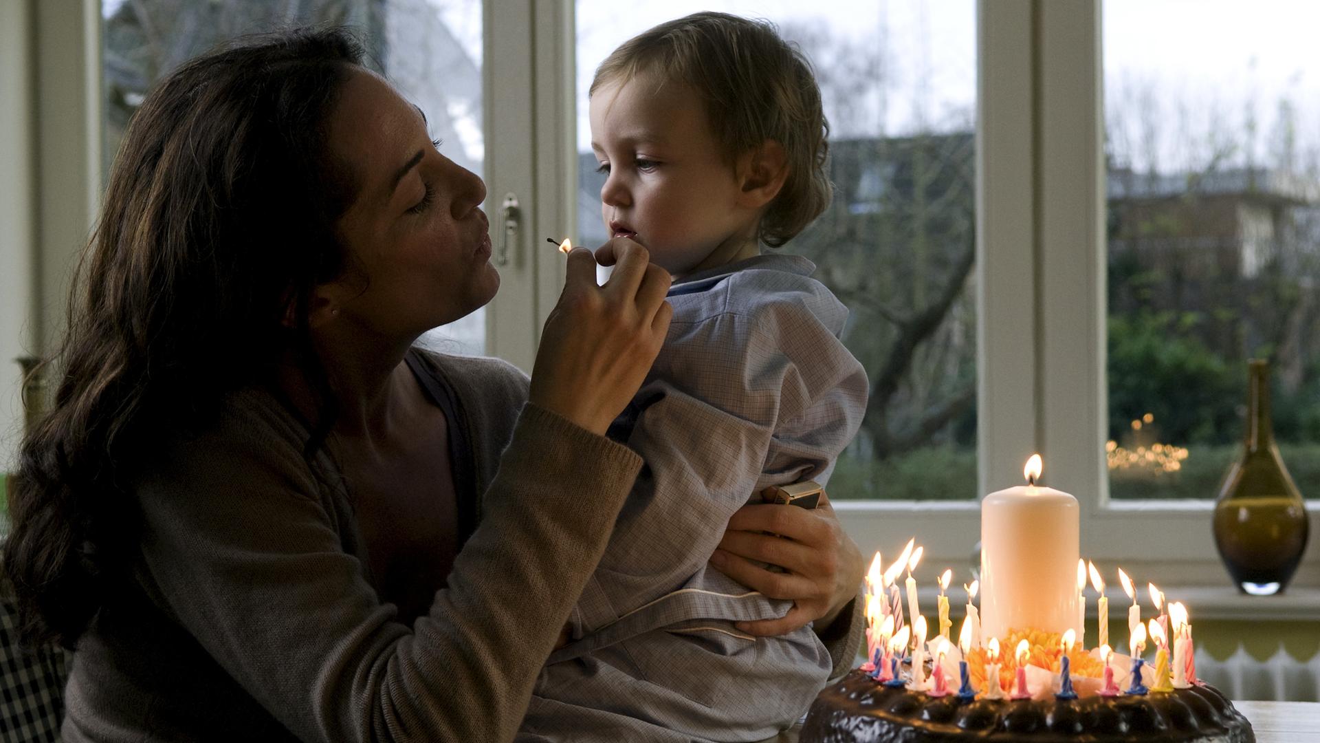 Jana Winter (Natalia Wörner) sitzt gemeinsam mit ihrem Sohn Leo am Küchentisch. Vor ihnen steht ein Geburtstagskuchen. Jana bläst mit Leo ein Streichholz aus.