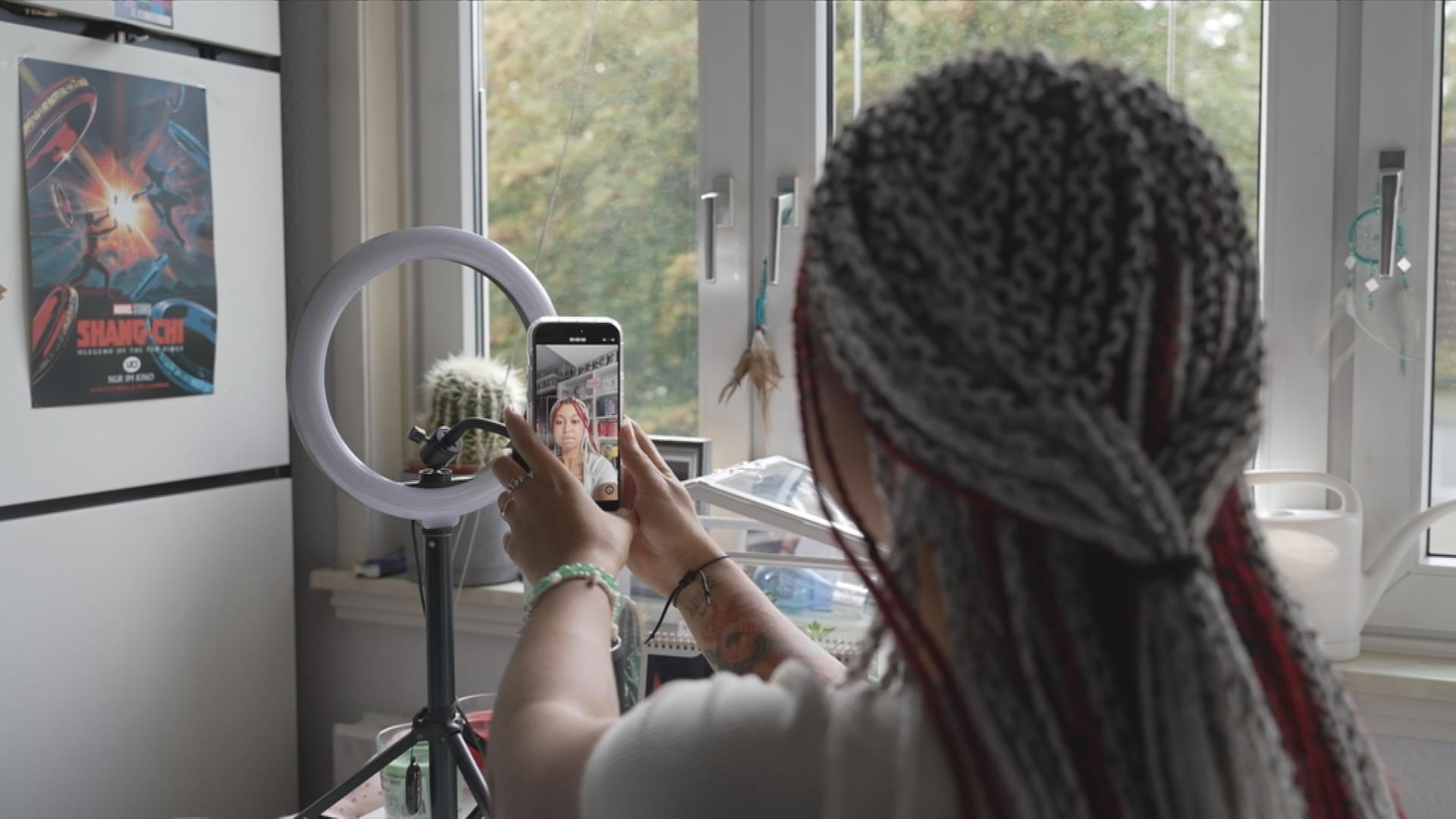 Auf dem Bild ist eine Tik-Tokerin zu sehen die gerade ein Selfievideo von sich aufnimmt.